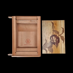 Ansicht der geöffneten Schatulle mit der roten Signatur des Ateliers Izumiya und dem Intarsien-Deckel mit Kamelienmotiv